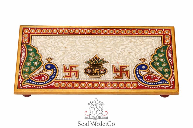 Pu&ograve; includere: Vassoio rettangolare decorativo in marmo con bordo dorato. Il vassoio presenta uno sfondo color crema con un motivo floreale, disegni di pavoni e simboli religiosi. Il vassoio &egrave; supportato da piccoli piedini in legno.