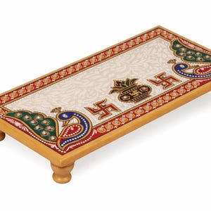 Pu&ograve; includere: Piattaforma decorativa rettangolare in legno con superficie color crema, ornata da un motivo floreale e colorati disegni di pavoni. La piattaforma presenta un bordo rosso e oro ed &egrave; sostenuta da quattro gambe arrotondate.