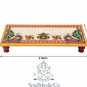 Pu&ograve; includere: Piattaforma rettangolare in legno con piano in marmo bianco, decorata con pavoni e simboli religiosi. La piattaforma &egrave; lunga 20 cm, larga 10 cm e alta 2,5 cm, sostenuta da quattro piccole gambe rosso scuro. Il design incorpora accenti rossi, verdi e dorati.