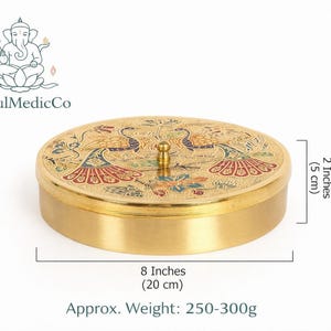 May include: A round, gold-colored container with a lid featuring a peacock design. The container is 8 inches (20 cm) in diameter and 2 inches (5 cm) high. The approximate weight is 250-300g. The SoulMedicCo logo is in the upper left corner.