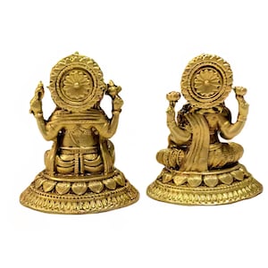 Pode incluir: Duas est&aacute;tuas douradas de uma divindade, provavelmente Lakshmi, s&atilde;o retratadas. Cada est&aacute;tua est&aacute; sentada em pose meditativa, com detalhes intrincados nas roupas e ornamentos. As est&aacute;tuas t&ecirc;m um design semelhante a um halo atr&aacute;s da cabe&ccedil;a. A base &eacute; decorada com um padr&atilde;o floral.