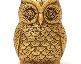 May include: A gold-colored owl figurine featuring detailed etched feather patterns across its body and wings. The owl has large, circular eyes with radiating lines and a pointed beak, with a textured finish that highlights the intricate plumage design.