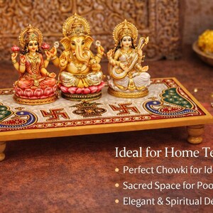 Pu&ograve; includere: Piattaforma decorativa in legno con tre statue religiose. La piattaforma ha una superficie colorata e decorata e poggia su gambe corte e arrotondate. Le statue sono di divinit&agrave; ind&ugrave;, con dettagli dorati e colorati. Una candela accesa e fiori sullo sfondo.