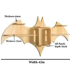Pu&ograve; includere: Mensola a muro in legno a forma di pipistrello con cinque ripiani. La mensola &egrave; alta 56 cm, larga 107 cm e ha una profondit&agrave; di 13 cm. La mensola &egrave; realizzata in legno naturale e ha un colore marrone chiaro.