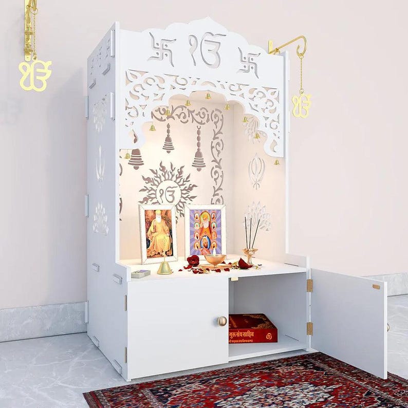 Ek-Onkar Home Temple with Inbuilt Focus Light, Brass Bells & Spacious Wooden Shelf- White Finish Gurudwara sahib for home and office Gifts.     Handcrafted white wooden home temple with ornate lotus backdrop, Om symbol and traditional Indian prayer decor