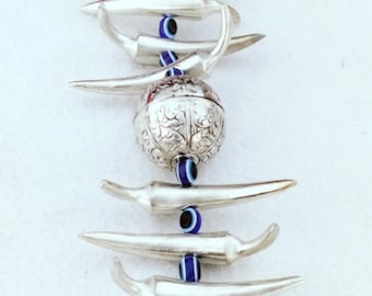 May include: Silver-toned metal charm featuring chili pepper shapes, a decorative orb, and small dangling charms. Blue and white evil eye beads are interspersed between the chili peppers. The charm is suspended from a loop at the top.