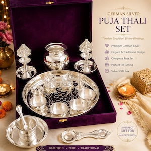 May include: A German silver Puja Thali set presented in a deep purple velvet box. The set includes a large circular tray with floral engravings, a small pot, two ornate oil lamps, several small bowls, a spoon, and a handled pouring vessel.