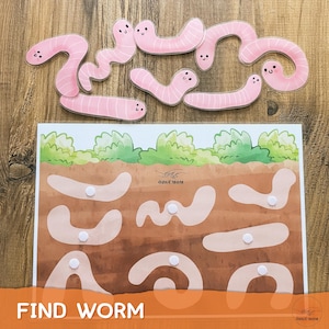 May include: A wooden educational toy with a board featuring a worm-themed design and several pink worm cutouts. The board has a brown and green illustration with the text "FIND WORM".