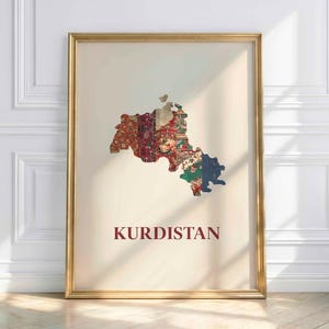 May include: A framed print featuring a map of Kurdistan, filled with colorful floral and patterned designs. The word "KURDISTAN" is printed in a dark red font below the map. The frame is gold.