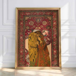 Op de afbeelding: Een ingelijste prent met een omhelzend paar, tegen een achtergrond van een rood patroonkleed en bloemmotieven. Het kunstwerk zit in een gouden lijst. Het paar is weergegeven in warme tinten goud, rood en groen.