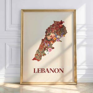 Op de afbeelding: Een ingelijste kunstdruk met de kaart van Libanon, gevuld met een bloemenpatroon in rood, roze en groen. Het woord "LEBANON" is in bordeauxrood gedrukt. De lijst is goudkleurig.