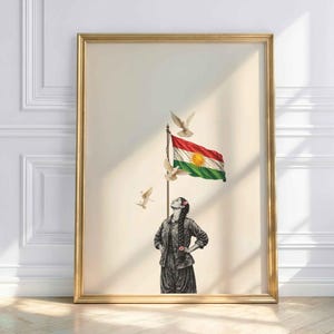 Könnte beinhalten: Gerahmter Kunstdruck mit einer Frau, die auf eine Flagge mit roten, weißen, grünen und gelben Farben blickt. Weiße Tauben fliegen um die Flagge. Das Kunstwerk befindet sich in einem goldenen Rahmen und lehnt an einer weißen Wand.