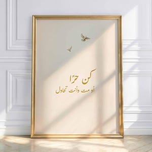 Puede incluir: Una impresión artística enmarcada con un marco dorado. La impresión presenta caligrafía árabe en oro, junto con dos pequeñas ilustraciones de pájaros. El fondo es de un color suave y neutro, y la estética general es minimalista y elegante.