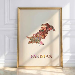 Könnte beinhalten: Ein gerahmter Kunstdruck mit einer Landkarte von Pakistan, die mit einem lebendigen Blumenmuster aus roten, rosa und orangefarbenen Blüten auf cremefarbenem Hintergrund gefüllt ist. Das Wort PAKISTAN steht in großen, bunten Buchstaben darunter.