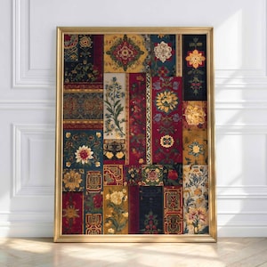 May include: A framed artwork featuring a patchwork design of floral and geometric patterns in shades of red, gold, navy, and cream. The artwork is displayed in a gold frame and leans against a white wall and wooden floor.