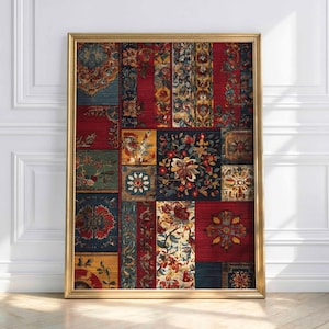 May include: A framed artwork with a patchwork design of floral and ornamental patterns in red, blue, gold, and green. The artwork is displayed in a gold frame and leans against a white wall.