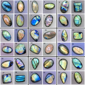 Pode incluir: Uma coleção de trinta e seis cabochões de labradorite polidos dispostos numa grelha, cada um numerado. Estas pedras preciosas exibem flashes iridescentes de azul, ouro, verde e roxo em várias formas ovais, retangulares e de lágrima com superfícies lisas.