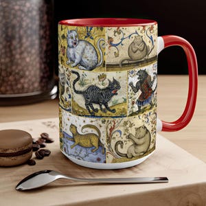 May include: A white ceramic mug with a red rim and handle. The mug features a colorful design of cats in a medieval style. The cats are depicted in various poses, including sitting, standing, and lying down. The background is a yellow and brown pattern.