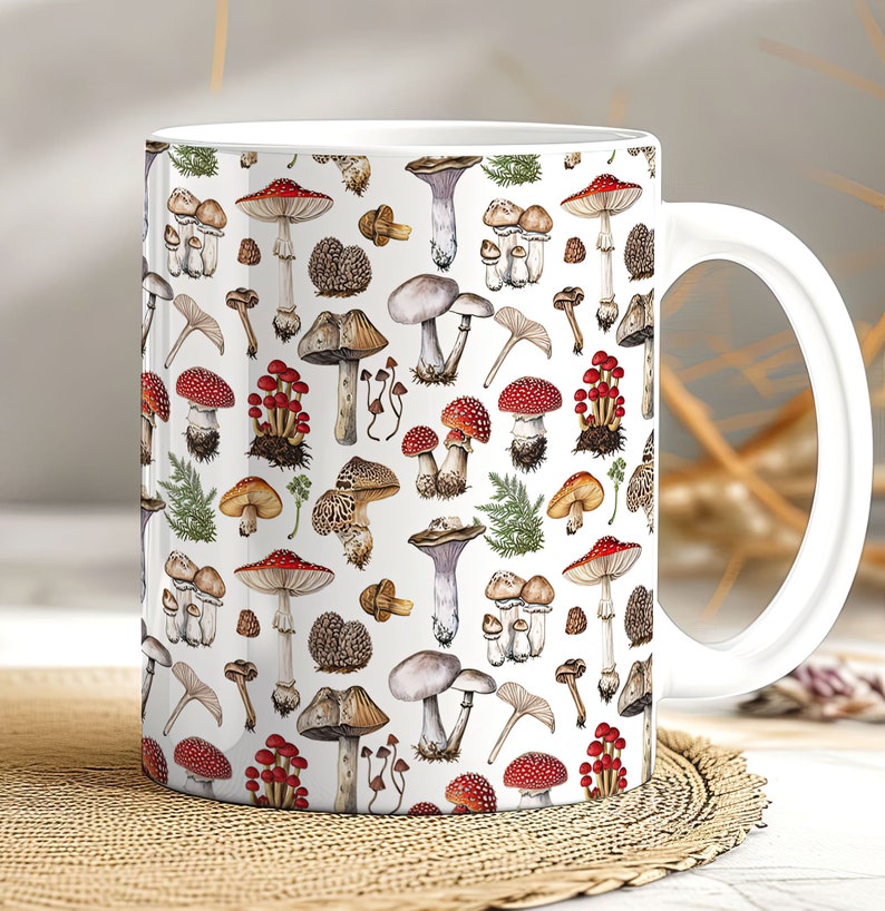 May include: White ceramic mug with a colorful mushroom pattern. The mug features a variety of mushrooms in different shapes, sizes, and colors, including red, brown, and white. The mushrooms are arranged in a repeating pattern on the mug.