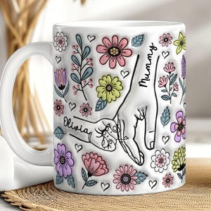 May include: White ceramic mug with a floral design and the words "Mummy" and "Olivia" printed on it. The design features a handprint of a mother and child holding hands.