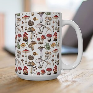 May include: White ceramic mug with a colorful mushroom pattern. The mug has a large handle and is filled with a variety of mushrooms in different colors and shapes.
