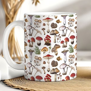 May include: White ceramic mug with a colorful mushroom pattern. The mug features a variety of mushrooms in different shapes, sizes, and colors, including red, brown, and white.