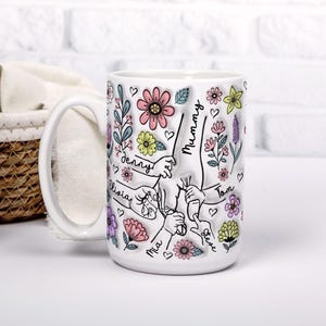 May include: White ceramic mug with a floral design and the names "Mummy", "Denny", "Olivia", "Mia", "Tom", and "Steve" written on it.