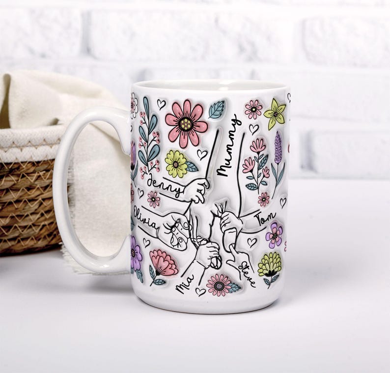 May include: White ceramic mug with a floral design and the names "Mummy", "Denny", "Olivia", "Mia", "Tom", and "Steve" written on it.
