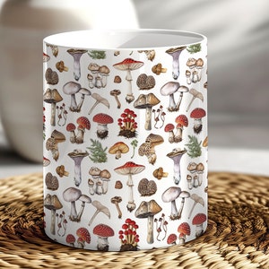 May include: White ceramic mug with a pattern of various types of mushrooms in shades of red, brown, white, and purple. The mushrooms are illustrated in a vintage style.