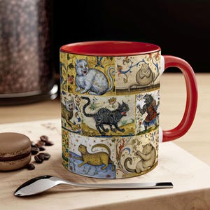 May include: A red and white ceramic mug with a colorful design of cats. The mug features a variety of cats in different poses, including a white cat with black ears, a black cat with a white chest, and a brown cat with a white belly. The mug is decorated with a floral pattern and a gold trim.