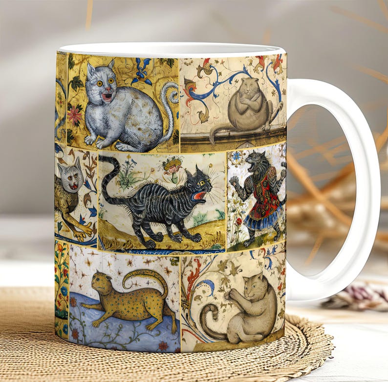 May include: White ceramic mug with a colorful design featuring multiple cats in different poses. The cats are depicted in a medieval style with intricate details and floral patterns.