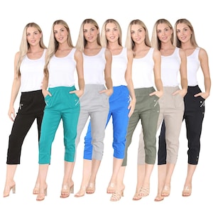 Può includere: Un gruppo di donne che indossano pantaloni capri in vari colori: nero, verde acqua, grigio, blu, verde oliva, beige e nero. Ogni donna indossa anche una canotta bianca. I pantaloni hanno tasche e una cerniera.