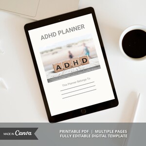 Op de afbeelding: Een digitale planner op een tabletscherm met de tekst "ADHD PLANNER" en "This Planner Belongs To" met een wazig beeld van een strand op de achtergrond. Het woord "ADHD" is gespeld met houten blokken.