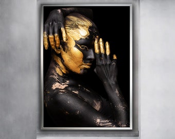 May include: A person with black paint on their body and gold paint on their face and hands. The person is looking to the side and their hand is covering part of their face.