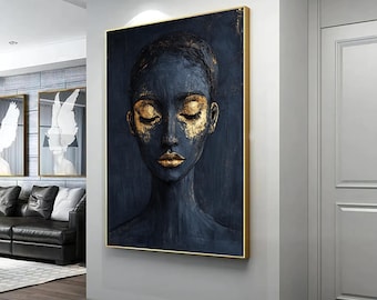 May include: A painting of a person's face with closed eyes. The face is painted in shades of blue and gold. The background is a dark blue.