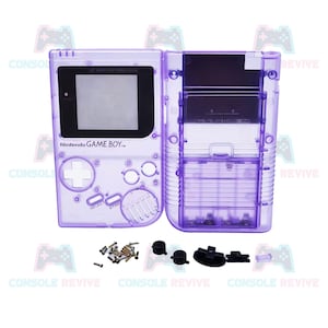 May include: A transparent purple Game Boy shell with the Nintendo Game Boy logo. The shell is open, revealing the internal components, including screws and buttons. The shell is designed for the original Game Boy.