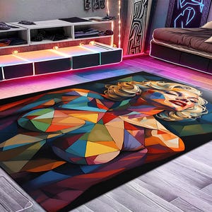 May include: A rectangular area rug featuring a geometric, low-poly style portrait of a blonde person with red lips. The design is composed of multicolored triangular shapes in shades of blue, orange, yellow, and red against a dark background.