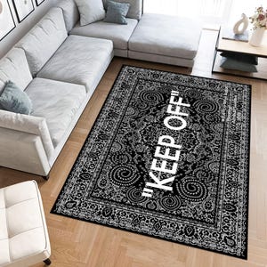 May include: Black and white area rug with a traditional paisley pattern and the text "KEEP OFF!" in white.