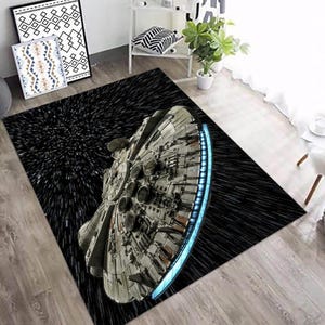 Puede incluir: Alfombra rectangular con una ilustración detallada de la nave espacial Millennium Falcon sobre un fondo negro espacial con rayas blancas. La alfombra tiene un borde azul brillante. Ideal para la decoración del hogar, aprox. 150 cm x 200 cm.