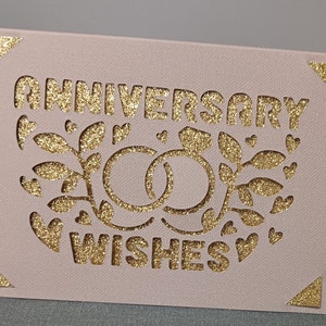 Tarjeta Deseos de aniversario dorado: Anillos de boda en color topo y dorado