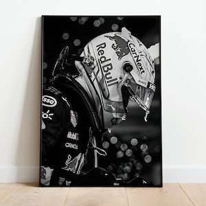May include: Black and white photograph of a racing driver wearing a white helmet with the words "Red Bull" and "CarNext" on it. The driver is wearing a black racing suit with various sponsor logos.