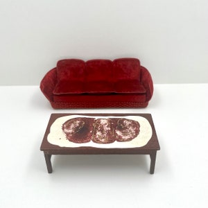 Peut inclure: Un canapé en velours rouge avec une table basse en bois brun avec un plateau blanc et un motif abstrait brun et blanc.