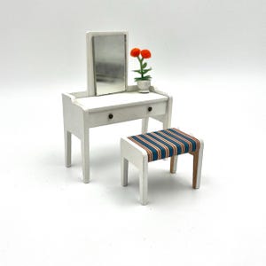 May include: White vanity set with a mirror, a drawer, and a stool with blue and orange striped upholstery.