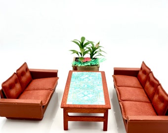 May include: A miniature living room set with two brown couches and a coffee table with a blue and white patterned top. A small potted plant sits on the table.