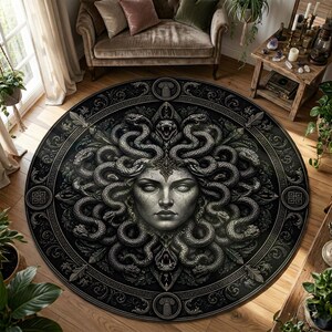 Può includere: Un tappeto rotondo, nero e grigio con un'illustrazione dettagliata del volto di Medusa e dei serpenti. Il tappeto ha un bordo decorativo con motivi di ispirazione greca ed è posto su un pavimento in legno.