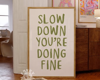 May include: A framed print with the text "SLOW DOWN YOU'RE DOING FINE" in green lettering on a white background.
