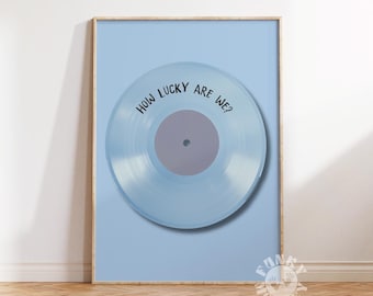 Puede incluir: Un disco de vinilo azul claro con el texto "How lucky are we?" impreso en él. El disco está enmarcado y se muestra en una pared azul claro.
