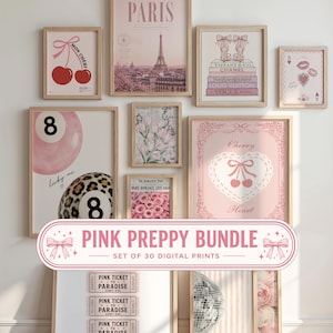 May include: A collection of framed wall art prints featuring pink-themed illustrations including the Eiffel Tower, cherries, high heels, flowers, billiard balls, and ticket stubs. The prints are displayed in light wood frames on a white wall.