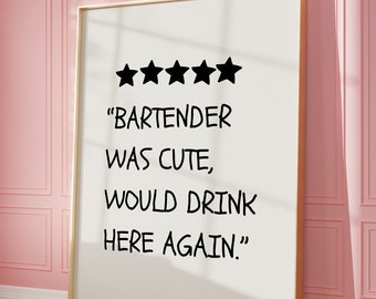 Puede incluir: Una impresión enmarcada con fondo blanco y marco dorado. La impresión presenta cinco estrellas negras en la parte superior y el texto "BARTENDER WAS CUTE, WOULD DRINK HERE AGAIN." en negro. La impresión está apoyada contra una pared rosa.
