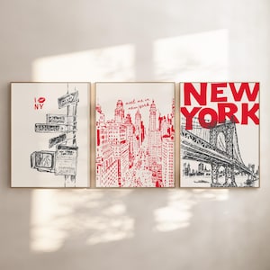 Op de afbeelding: Drie ingelijste prints met een New York City-thema. De eerste print heeft een rood hart met de letters "I NY" en straatnaamborden. De tweede print toont een rood-witte illustratie van de skyline van New York City. De derde print heeft een zwart-witte illustratie van de Brooklyn Bridge met de woorden "NEW YORK" in rode letters.